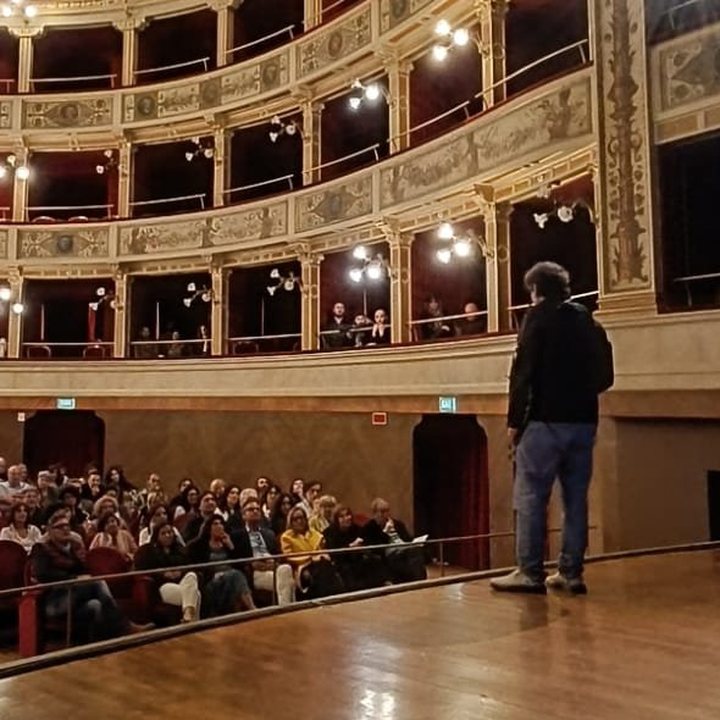 Pier Giorgio Caselli sul palco di un teatro, davanti al pubblico
